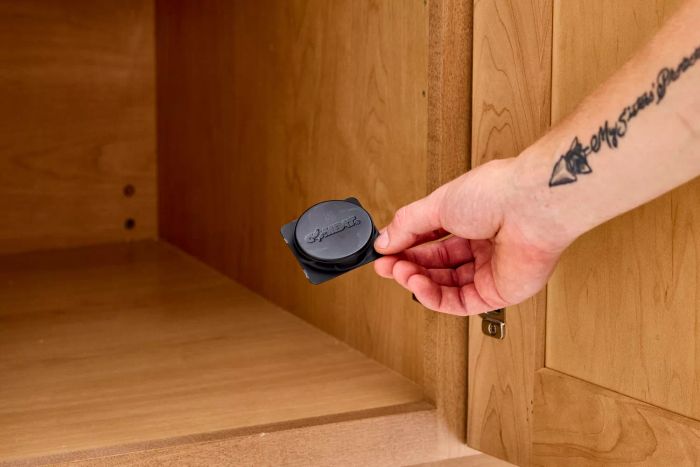 A hand setting Combat Max Roach Killing Bait inside a cabinet