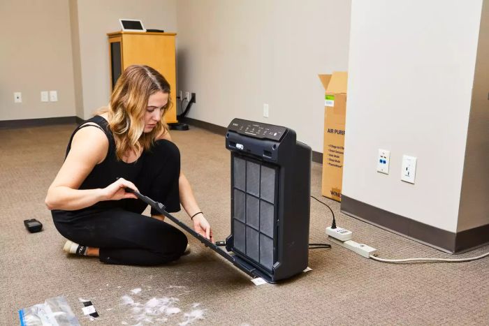 A person opening the front panel of the Winix 5500-2 4-Stage True HEPA Air Purifier