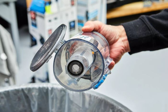A hand emptying the dirt from the dust tank of the BLACK+DECKER Powerseries Extreme Cordless Stick Vacuum Cleaner