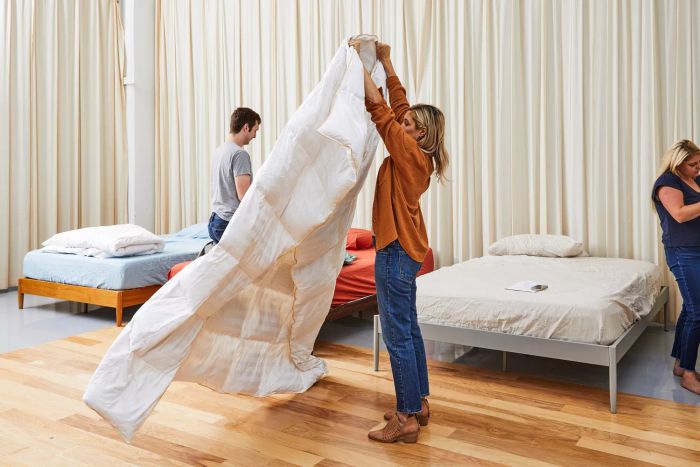 A woman lifting the Alwyn Home All Season Down Comforter.