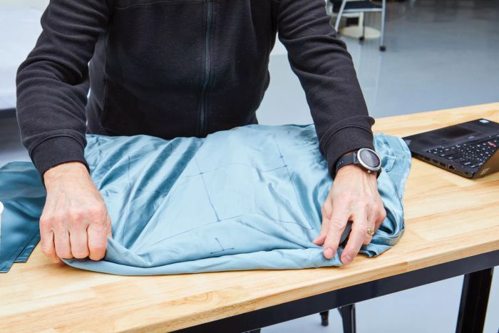 A person neatly folding a Colorado Home Co. Mulberry Silk Bed Sheets Set on a table