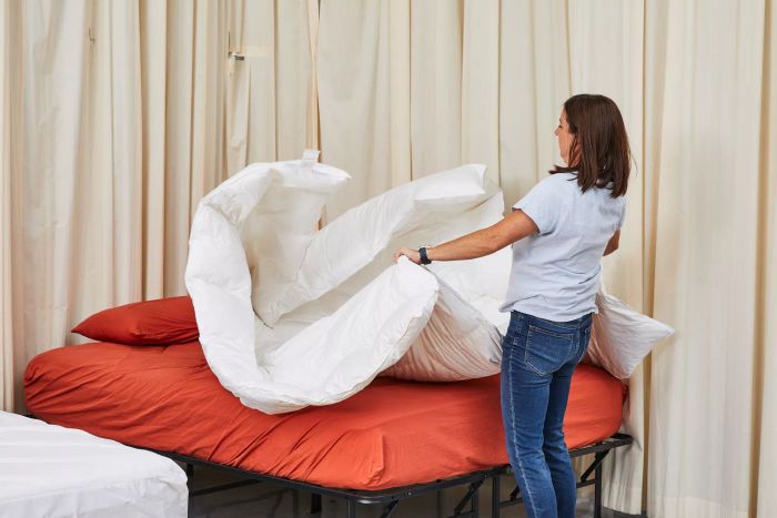 A person raising the Kassatex European White Goose Down Comforter, demonstrating its light and fluffy texture.