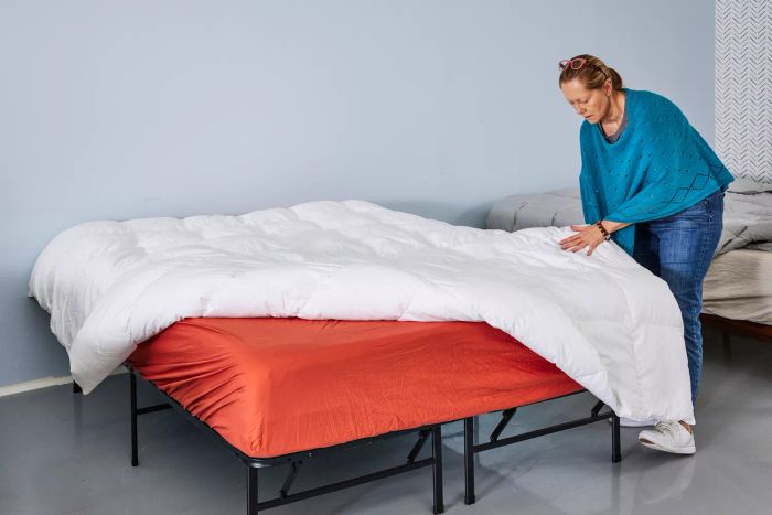 A person adjusting the bed with the Kassatex European White Goose Down Comforter