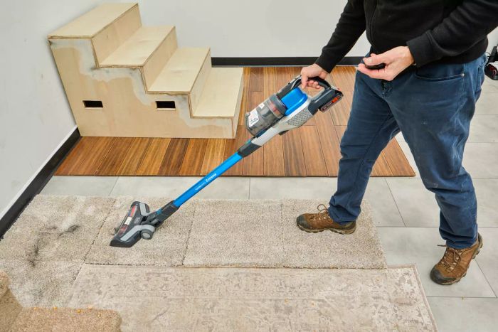 A person using the BLACK+DECKER Powerseries Extreme Cordless Stick Vacuum Cleaner to clean a carpeted floor