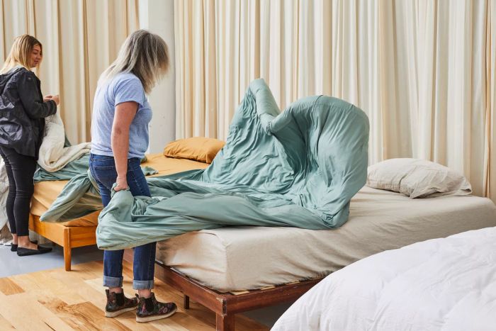 A person adjusting the bed with the Egyptian Bedding Luxurious Queen Size Goose Down Feather Comforter