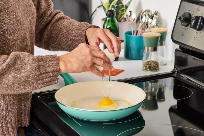 A person fries an egg in the GreenPan Rio Ceramic Nonstick 16-Piece Cookware Set pan.
