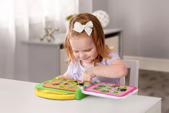 A young girl is pressing the buttons on the LeapFrog 100 Animals Book to play sounds and learn.