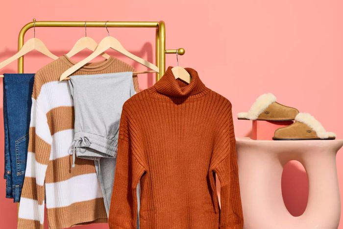 Various garments hanging from a clothing rack along with Ugg slippers set against a soft pink backdrop.