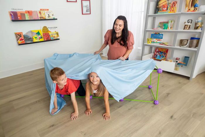 Children are enjoying themselves hiding inside the Crazy Forts Original, placed on a wooden surface.