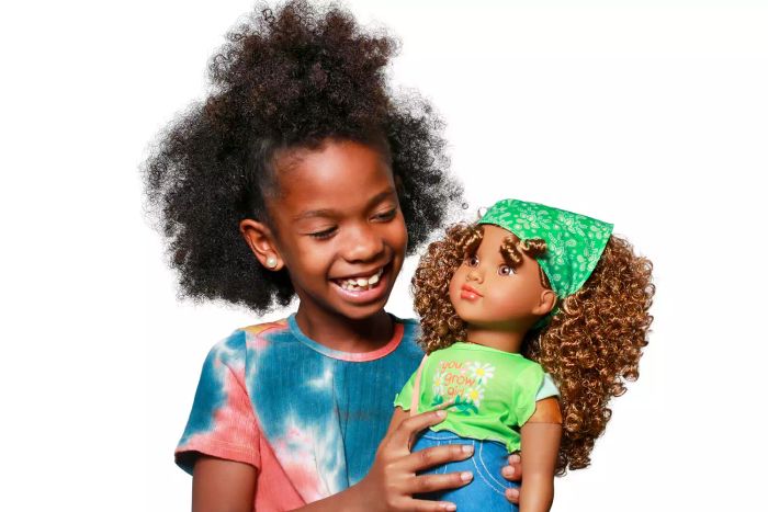 A child is happily holding the Positively Perfect Willow Baby Doll in their hand.