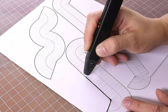 A person is using the MYNT3D Super 3D Pen to trace curved lines on a sheet of paper with a gridded pattern