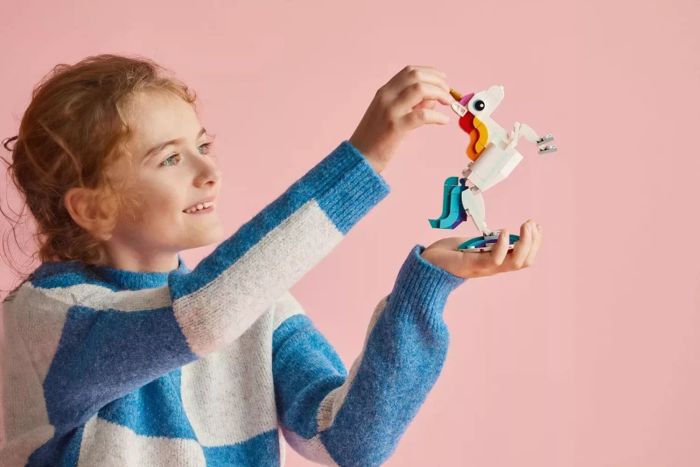 A child is enjoying the LEGO Creator 3-in-1 Magical Unicorn, holding it in their hands