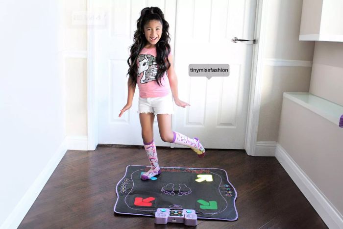 A girl dances on the blue arrows of the Kidzlane Light Up Dance Pad