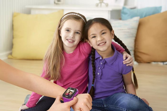 A person is setting the wallpaper on a VTech Kidizoom Kids Smartwatch DX2, while two children sit in front of them