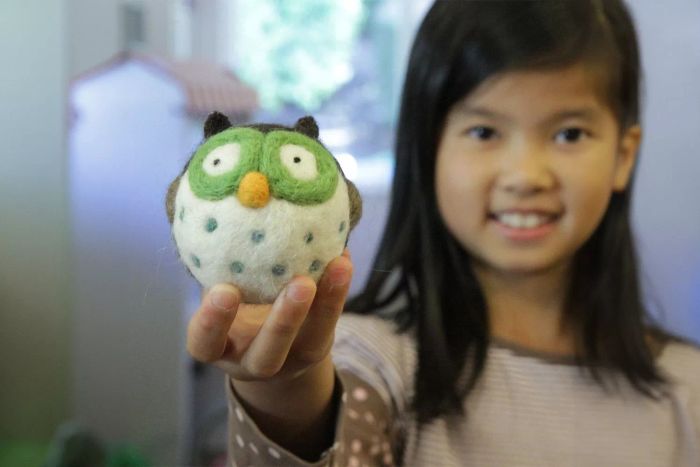 A child is holding a tiny owl crafted from the Woolbuddy Needle Felting Starter Kit