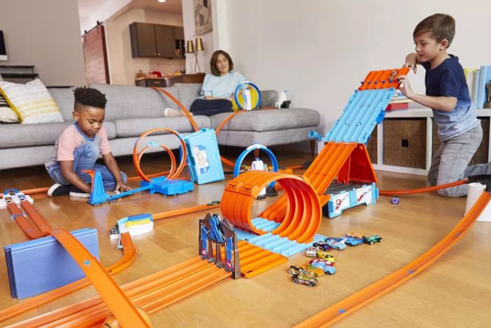 Kids are having fun with the Hot Wheels Race Crate Toy Car Track Set on a wooden surface