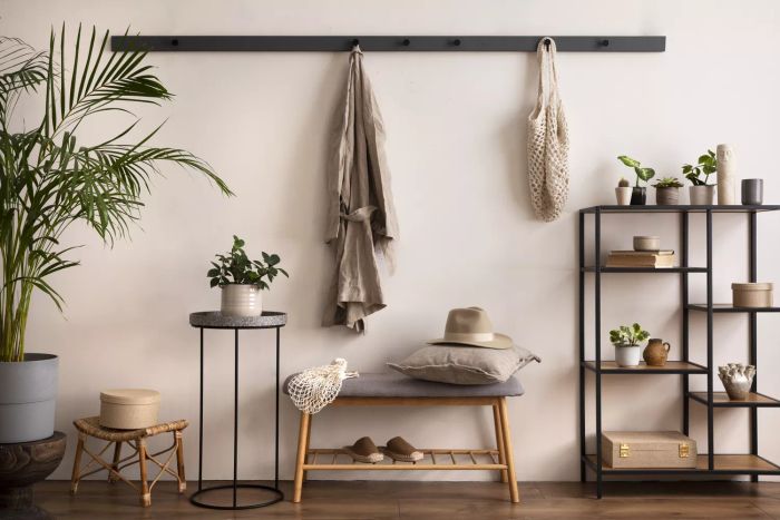 A chic and cozy entryway featuring a grey bench, black console table, coat hanger, and a lamp. Beige walls complete the look. Perfect for home decor inspiration.