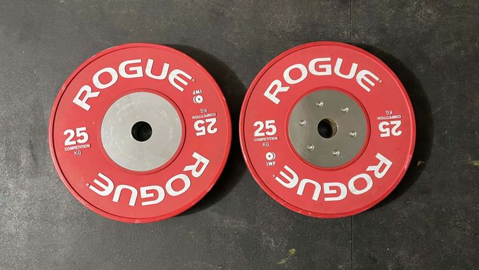 A red 25kg bumper plate, front and back. The markings are the same on both sides, but one side features visible hardware at the center.