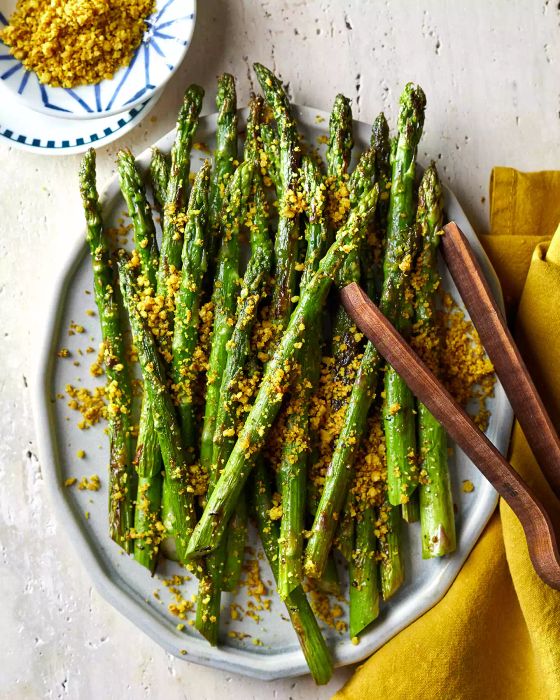 Roasted Asparagus With Flax Seed-Walnut Crumble on a Serving Platter With Wooden Tongs for Serving
