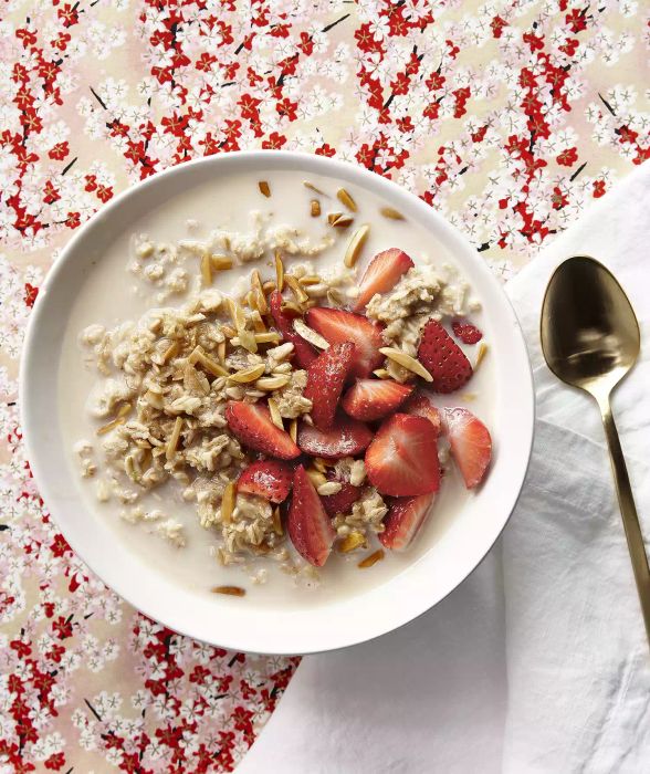 Overnight Oats with Strawberries and Toasted Almonds in a White Bowl with a Metal Spoon for Eating