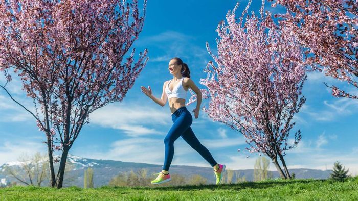 a woman jogging amidst blooming cherry blossoms