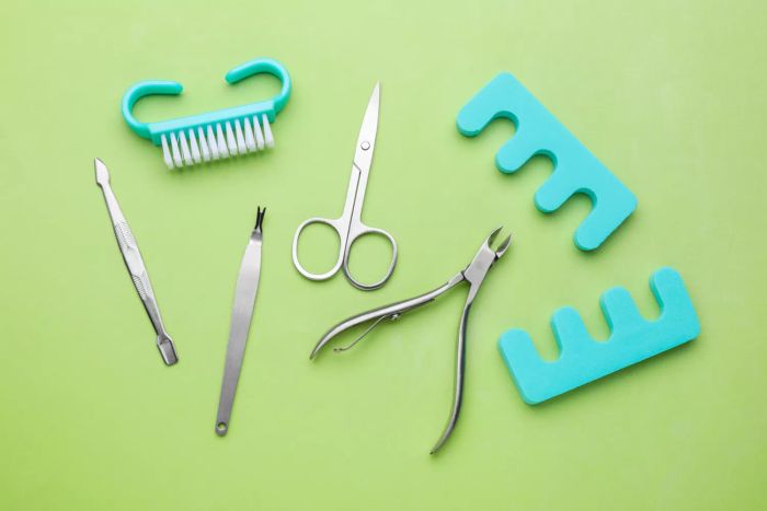 A collection of pedicure tools on a soft green background, viewed from above
