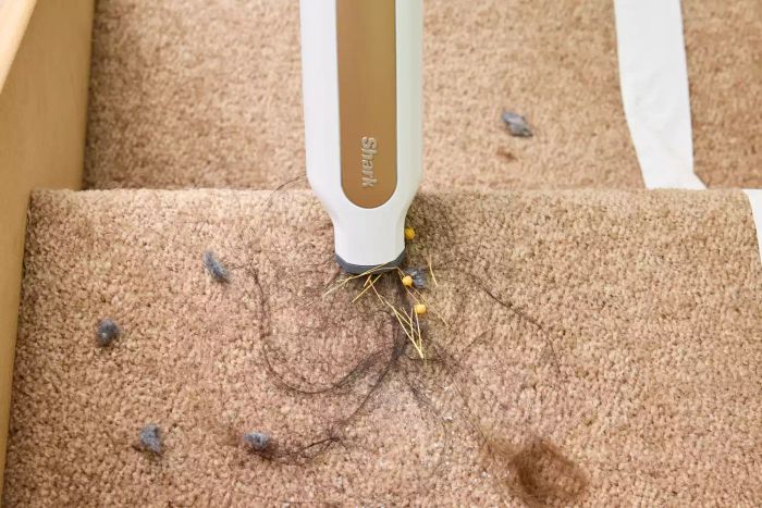 A close-up view of the Shark WS642AE Wandvac Cordless Stick Vacuum with Self-Empty Charging Base as it removes dirt from a step.