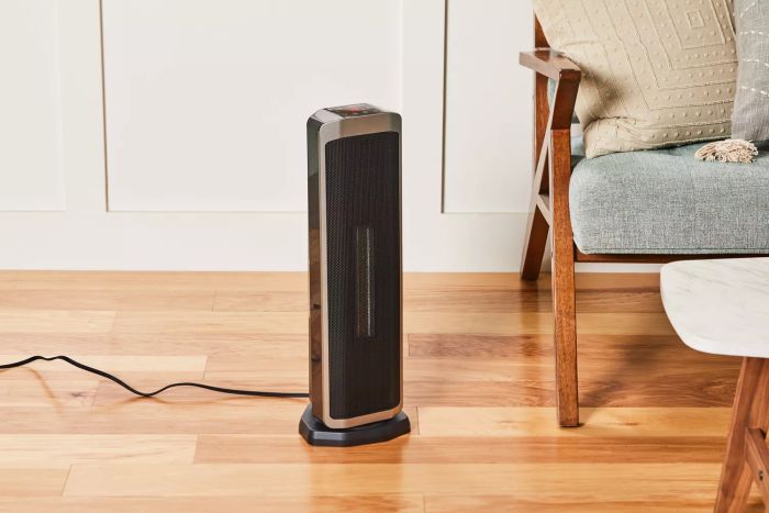 Better Homes & Gardens 23-Inch Electric Ceramic Tower Heater placed on a wooden floor beside a couch