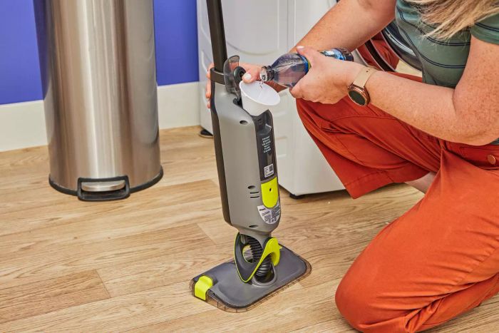 A person is adding water to the tank of the Shark VM252 Vacmop Pro Cordless Wet/Dry Stick Vacuum