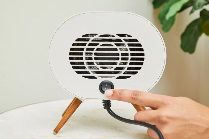 A person turning on the BabyExo Small Space Heater by pressing the power button