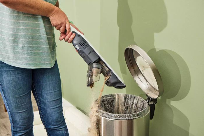 A person misses the trash can while emptying the Shark WS642AE Wandvac Cordless Stick Vacuum