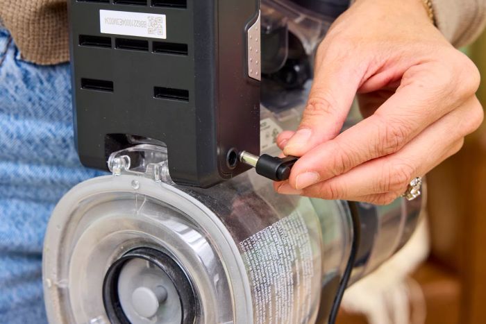A close-up of a hand plugging the Tineco Pure One S11 Vacuum into a socket