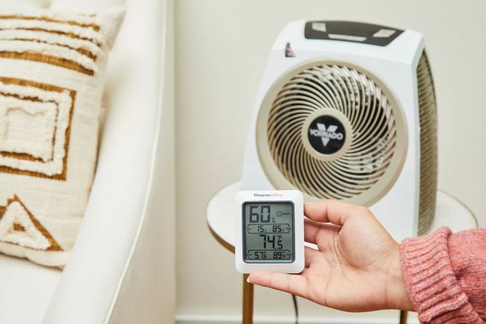 A person measuring the temperature near the Vornado AVH10 Vortex Heater