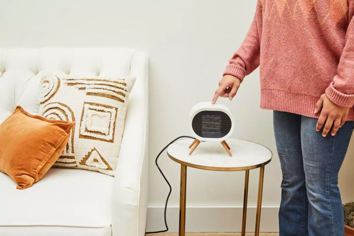 A person adjusting a button on the BabyExo Small Space Heater