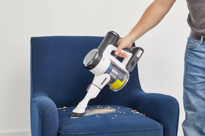 Cleaning crumbs from a navy chair with the Tineco Pure One S15 Pro Cordless Stick Vacuum Cleaner.
