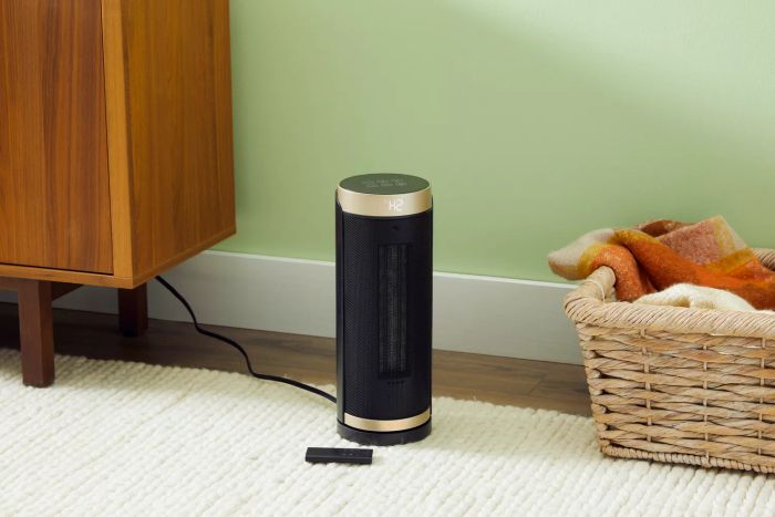Dreo Solaris Slim H3 Space Heater and its remote placed on a rug near a basket and side table