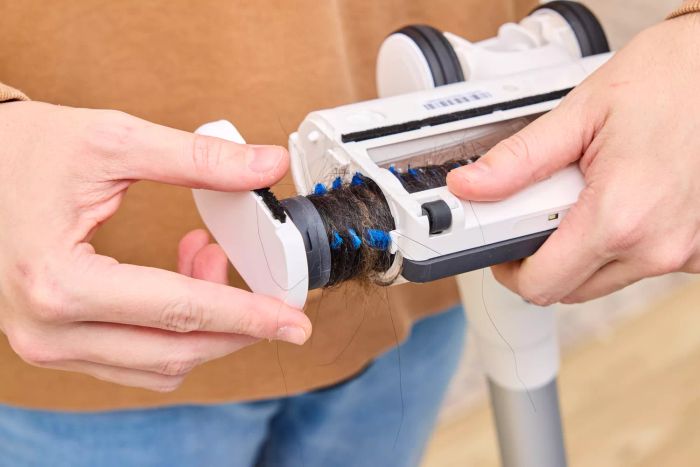 A person detaching a part of the Tineco Pure One S15 Pro Vacuum that is clogged with hair.