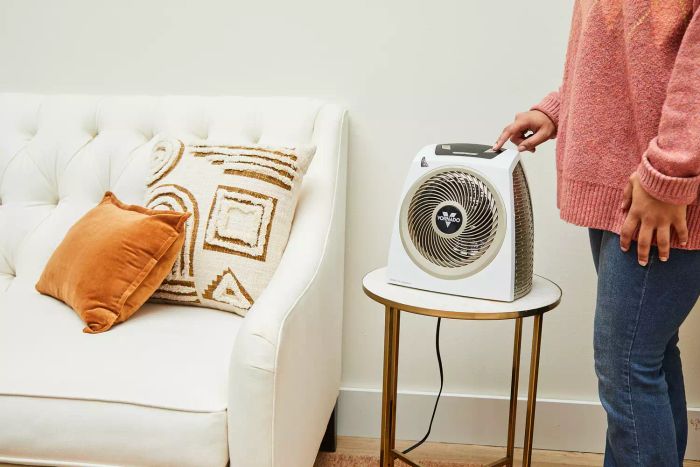 A person adjusting a button on the Vornado AVH10 Vortex Heater