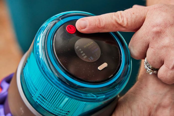 A close-up of a finger pressing a button on the Dyson Gen5detect Cordless HEPA Vacuum.