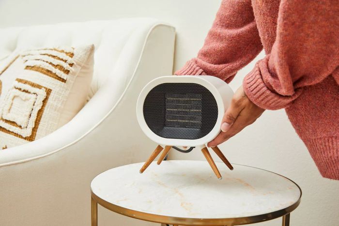 A person placing the BabyExo Small Space Heater on a side table