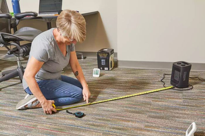 A person using a tape measure to gauge the distance from the Kismile Portable Electric Space Heater