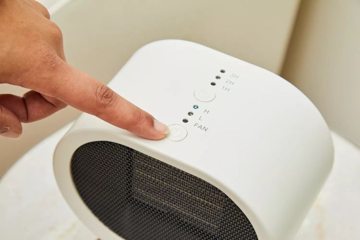 A person indicating the power button on the BabyExo Small Space Heater