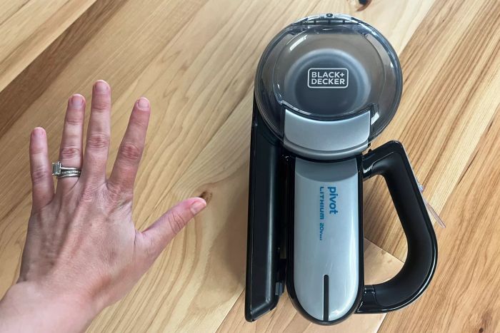 A person compares the size of their hand to the BLACK+DECKER 20V Max Handheld Vacuum, Cordless, Grey (BDH2000PL).