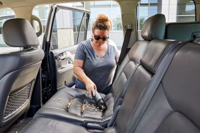 Person using Bissell AeroSlim Cordless Handheld Vacuum to clean a car seat