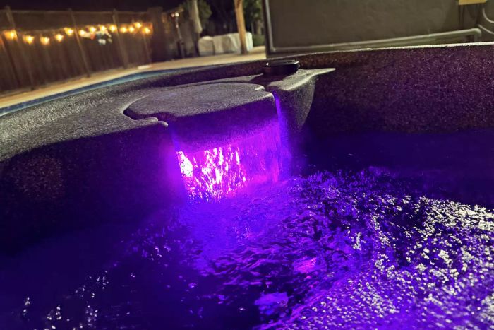 A purple light glowing at night in the Aquarest Spas, Powered By Jacuzzi® Pumps Premium AR300 2-Person 20-Jet Oval Plug & Play Hot Tub with Ozonator