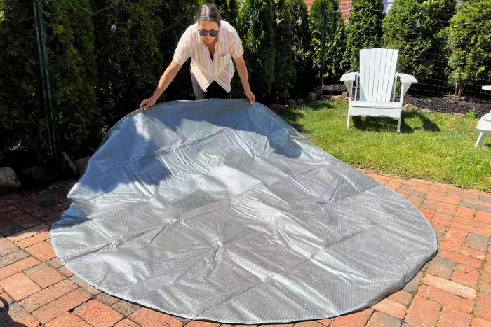 A person sets up the Intex PureSpa Plus 6-Person Portable Inflatable Hot Tub on a patio.