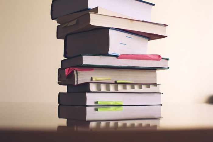 A pile of textbooks adorned with sticky notes