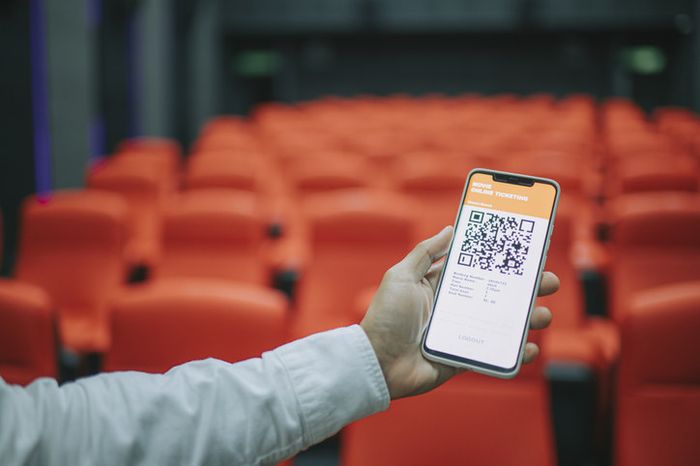 A man using a mobile app to book e-tickets for a movie, selecting seats in a cinema hall