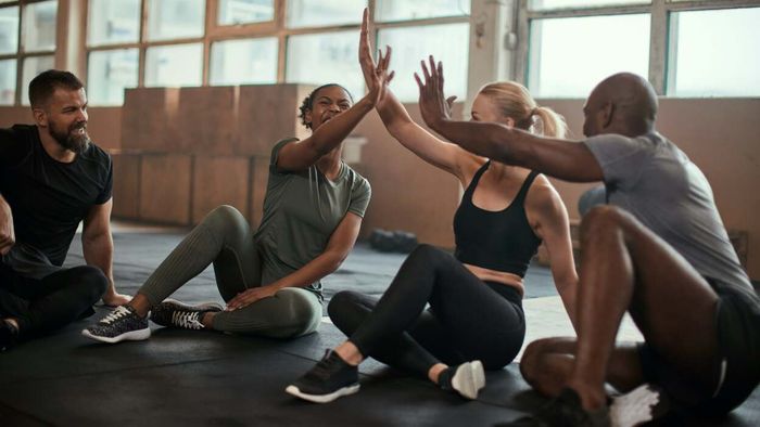 group of friends celebrating with high-fives at the gym