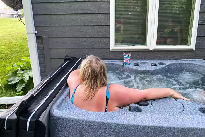 A person relaxing in the Aquarest Spas Select 150 4-Person 12-Jet Rectangular Plug-and-Play Hot Tub